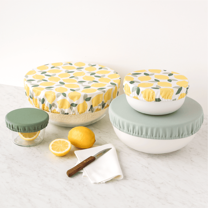 Set of food storage containers with lemon pattern and two shades of green on a white surface