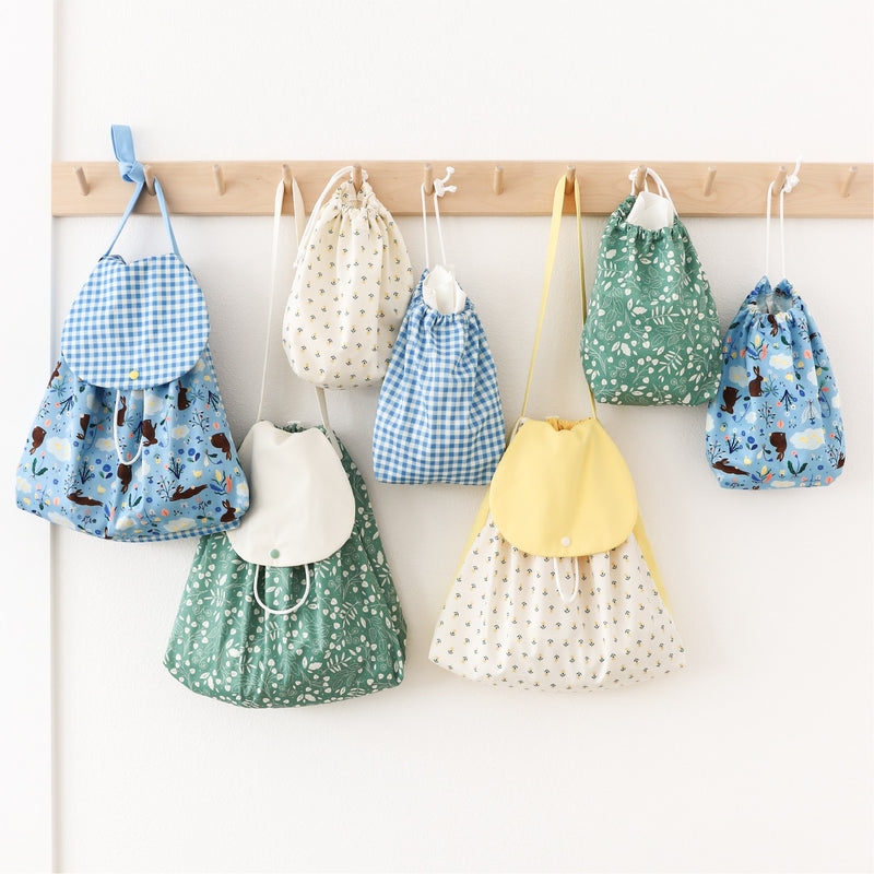 Ditty Bags and Day Bags in the Flora Waycott collection hanging from wooden pegs.