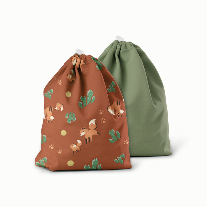 Two drawstring bags, one brown with fox and plant pattern and one green, on a white background.