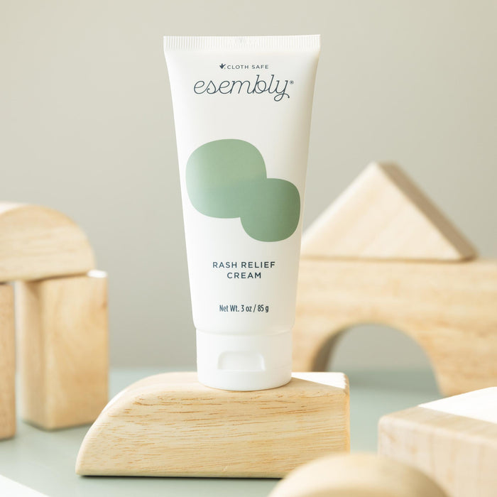 Rash Relief Cream (a white tube with a green splotch and dark blue text) sitting on wooden blocks