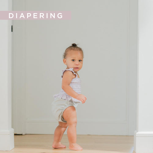 a little girl in a cloth diaper walking in a house