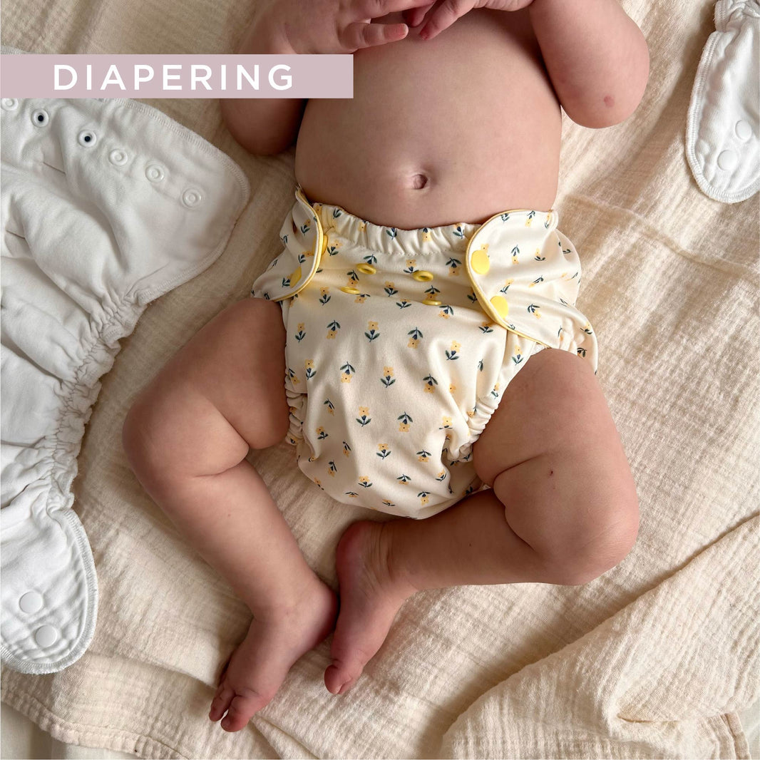 Baby in floral cloth diaper cover on blanket