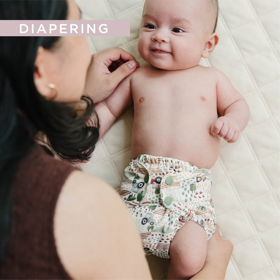 Mom smiling at baby in a tractor cloth diaper
