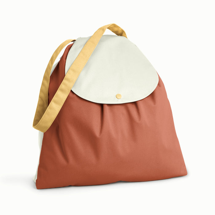 Front view of Esembly Day Bag a light brown strap and back, a warm brown front, and a cream flap.