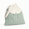 Front view of Esembly Day Bag with a cream flap, dark green back, and mid-tone green with an outlined check pattern