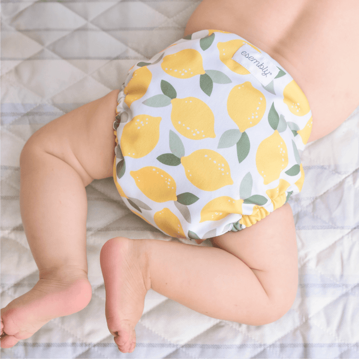 Baby wearing a diaper with lemon pattern on a textured surface
