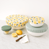 Set of food storage containers with lemon pattern and two shades of green on a white surface