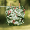 A Peek-a-Bear Outer (mid-tone and light green trees in the background with illustrated brown bears peeking out) hanging on a laundry line with clothing pins