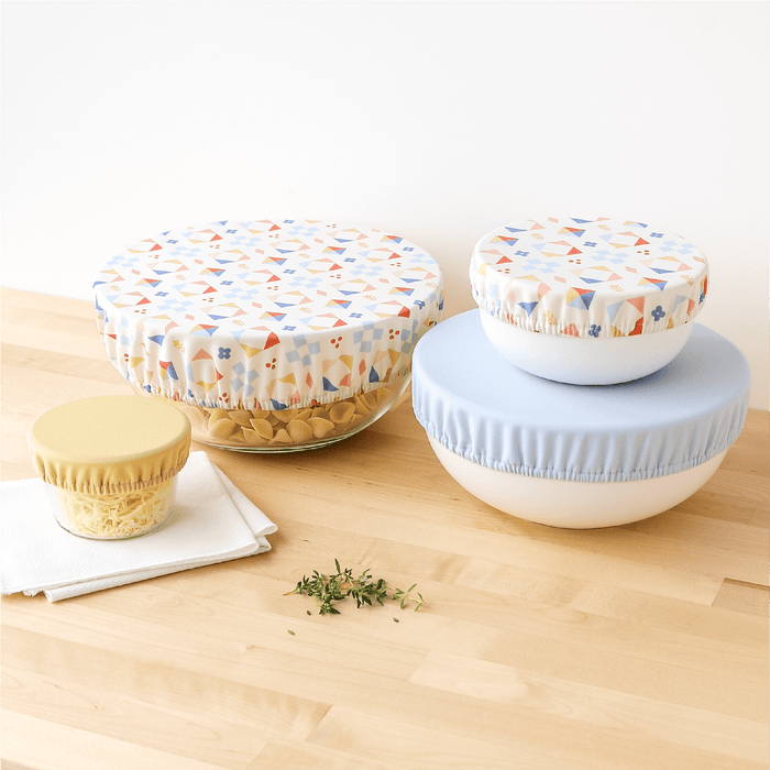 Set of glass containers with colorful bowl caps on a wooden surface