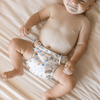 Baby wearing a patterned diaper on a soft surface