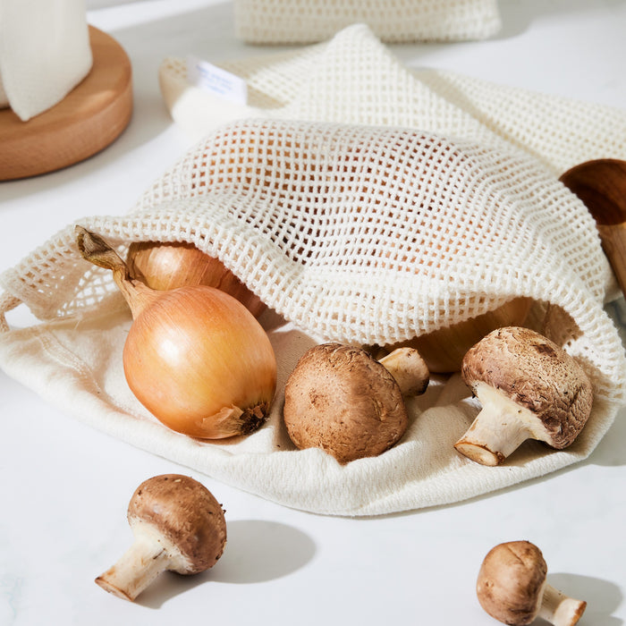 Mushrooms and onions coming out the top of a produce saver that's sitting on a marble countertop