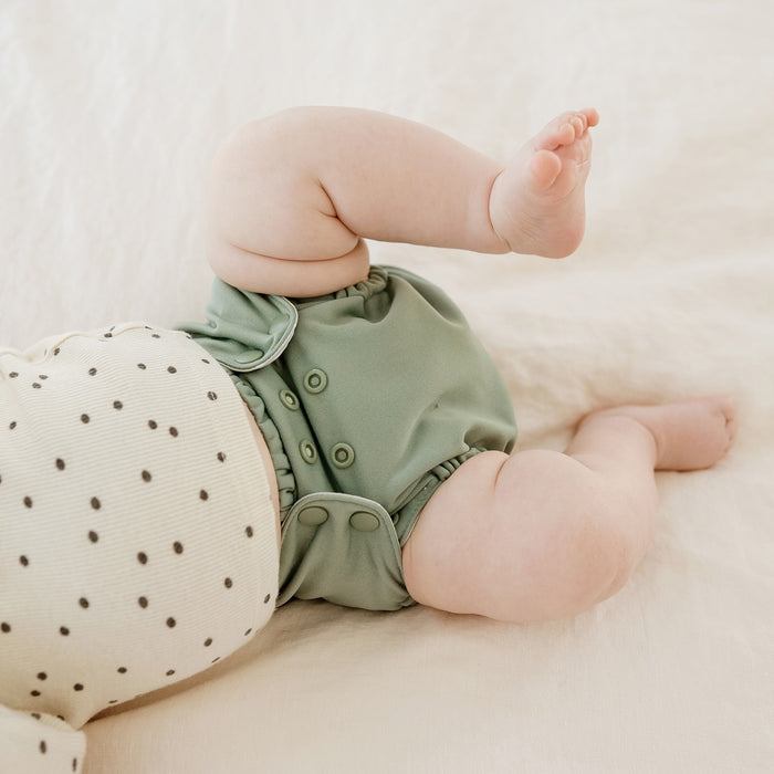 A mid-green color Outer on a baby with a white shirt with black polkadots