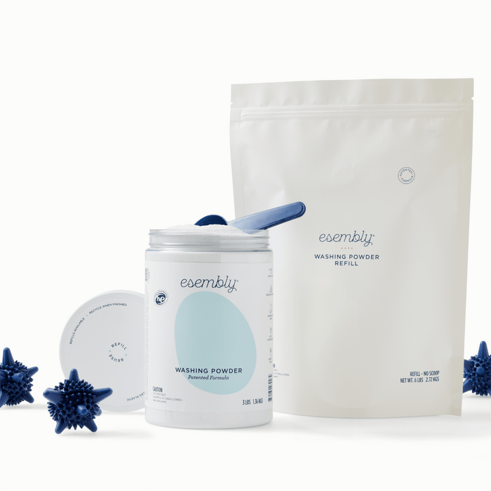 Esembly Washing Powder in a canister next to Esembly Washing Powder in our Refill Bag surrounded by navy blue spiky Agitators