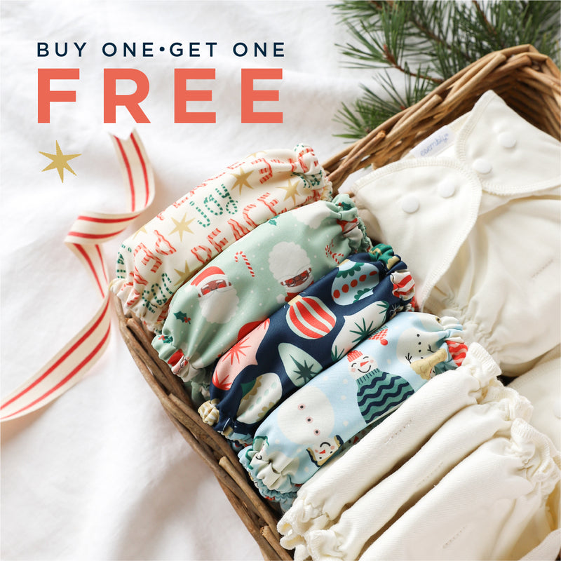 Stack of cloth diapers with Christmas-themed designs in a basket, promotional text 'Buy One Get One Free' on a white background.