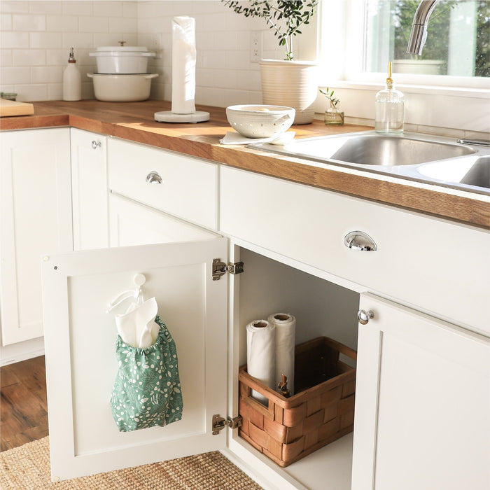 Botany (green background with white leaves) paperless towels hanging on the inside of a cabinet door in a kitchen