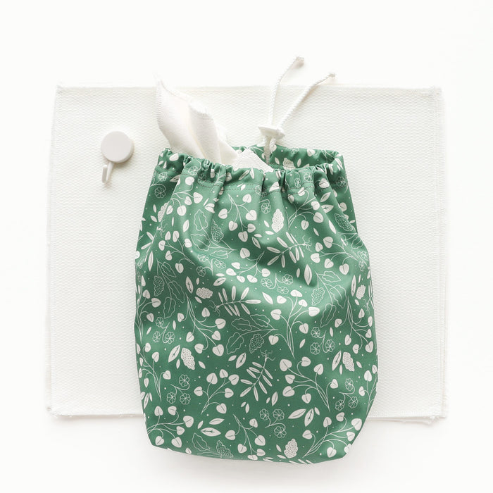 Botany (green background with white leaves) Ditty Bag next to a stack of paperless towels and a white hook