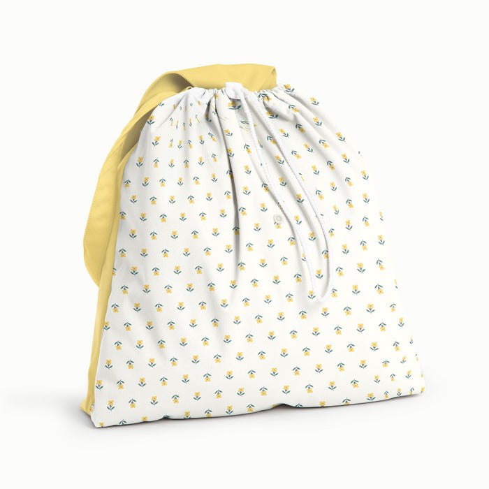 Front view of an Esembly Day Bag with the front in Buds (a parchment background with tiny yellow and green flowers) and the back, strap, and flap all in a soft, buttery yellow