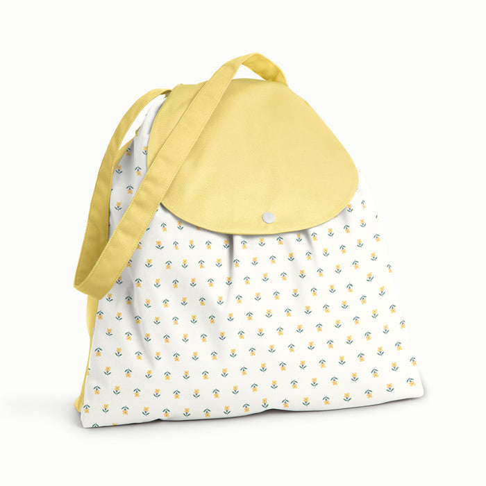 Front view of the Buds Esembly Bag (front is in Buds - a parchment background with tiny yellow and green flowers) and the flap, back, and strap in Buttercup (a soft, buttery yellow)