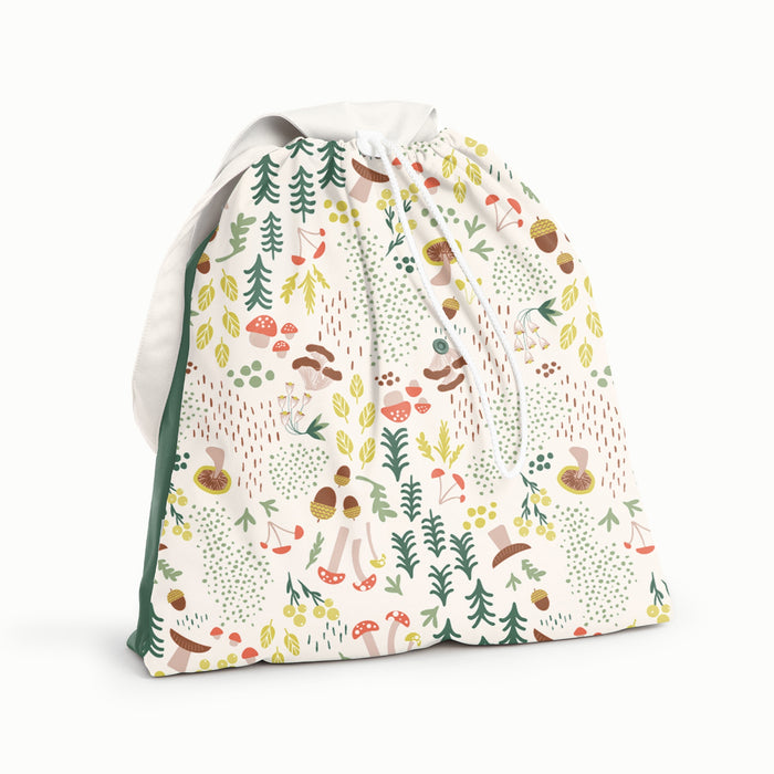 Front view of Esembly Day Bag in Fantastic Fungi with a front body with the Fantastic Fungi Pattern (an off-white background with colorful mushroom, trees, and leaves illustrations), a dark green back, and a white flap and strap
