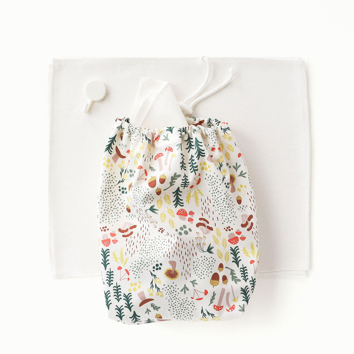 A stack of paperless towels with a ditty bag on top in Fantastic Fungi (an off-white background with colorful mushroom, trees, and leaves illustrations)