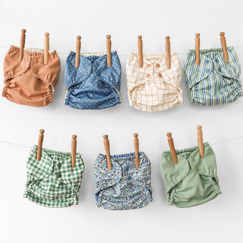 Set of colorful baby diapers on a clothesline against a white background