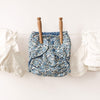 Blue floral-patterned diaper with wooden hangers on a white background