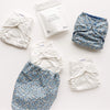Set of floral cloth diapers and laundry detergent on a white background
