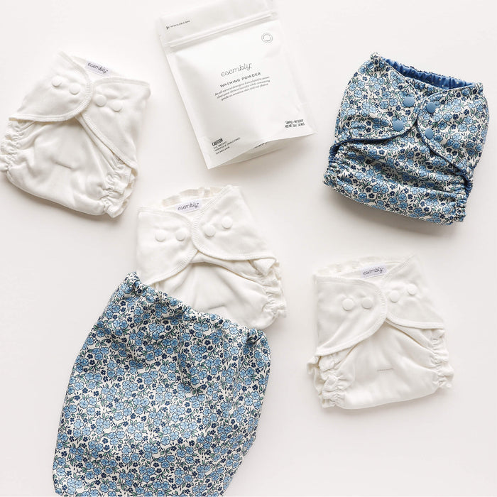 Set of floral cloth diapers and laundry detergent on a white background
