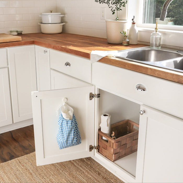 Gingham (mid-tone blue and white gingham pattern) paperless towels hanging on the inside of a cabinet door in a kitchen