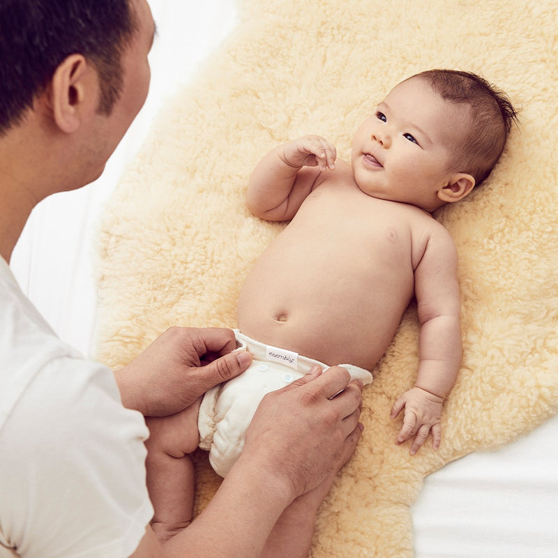 A baby being changed into an Esembly cloth diaper