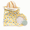 Reusable bread bag with lemon pattern containing bread, next bowl caps