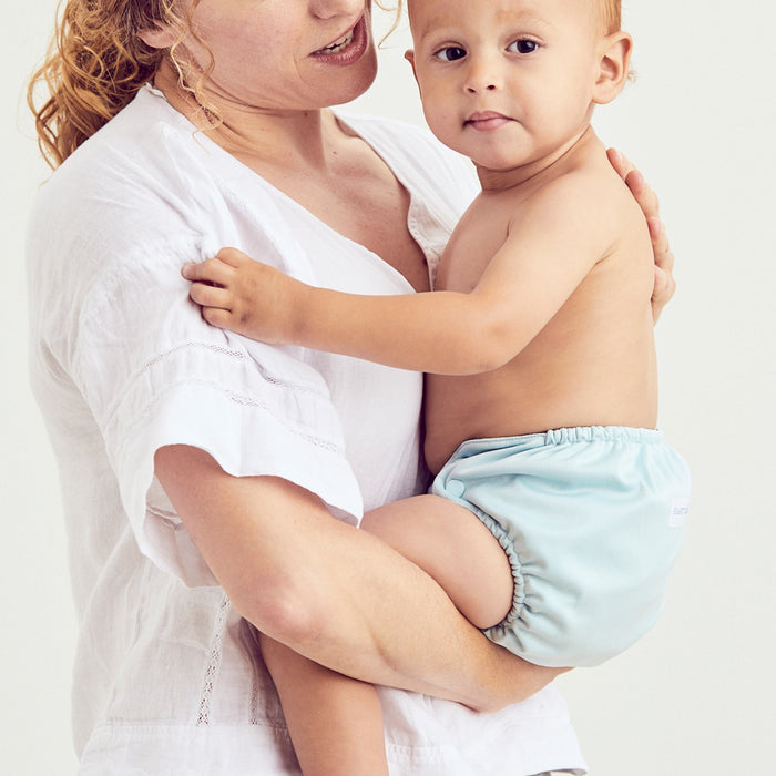 Mom wearing a white shirt holding baby wearing an Outer in a light blue color