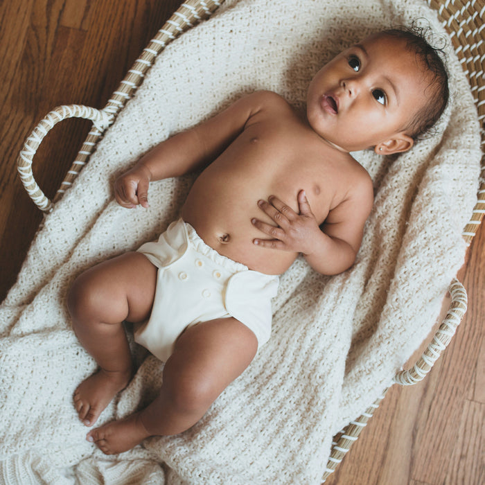 A baby wearing an Outer with an off-white cream color