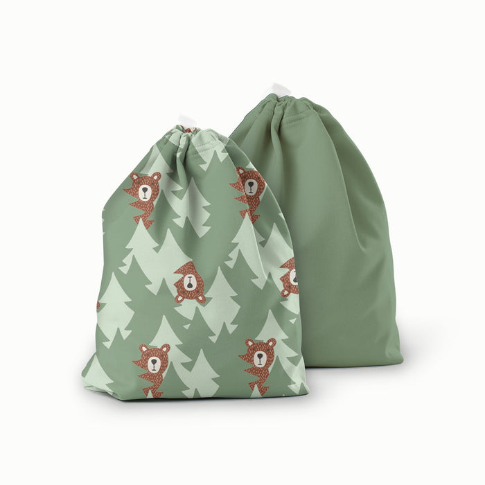 A ditty bag duo in Peek-a-Bear (mid-tone and light green trees in the background with illustrated brown bears peeking out) and Aloe (a mid-tone green solid)