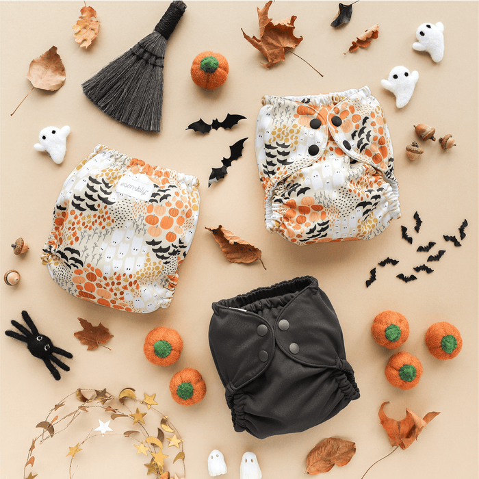 Halloween-themed baby diapers with pumpkins, ghosts, and brooms on a beige background