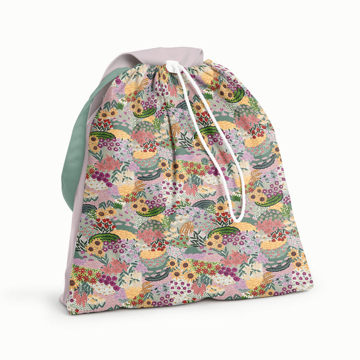 Front view of Esembly Day Bag with a body in our Botanic Garden pattern (colorful florals hand painted by illustrator Sara Boccaccini Meadows), and a green strap, and amethyst flap and back