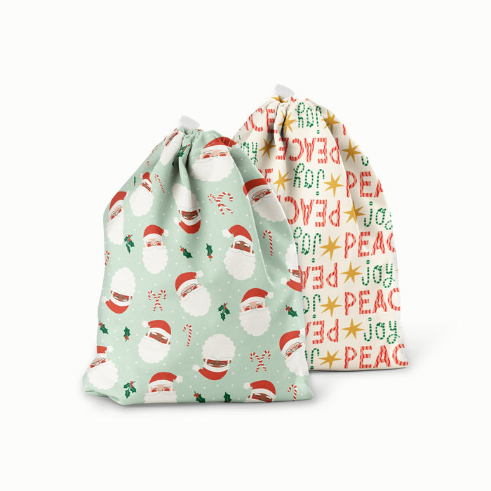 Ditty Bag in Santas (a mint green Outer with illustrated Santa heads, mistletoe, and candy canes) and Peace + Joy (a white background with red peace and green joy words)