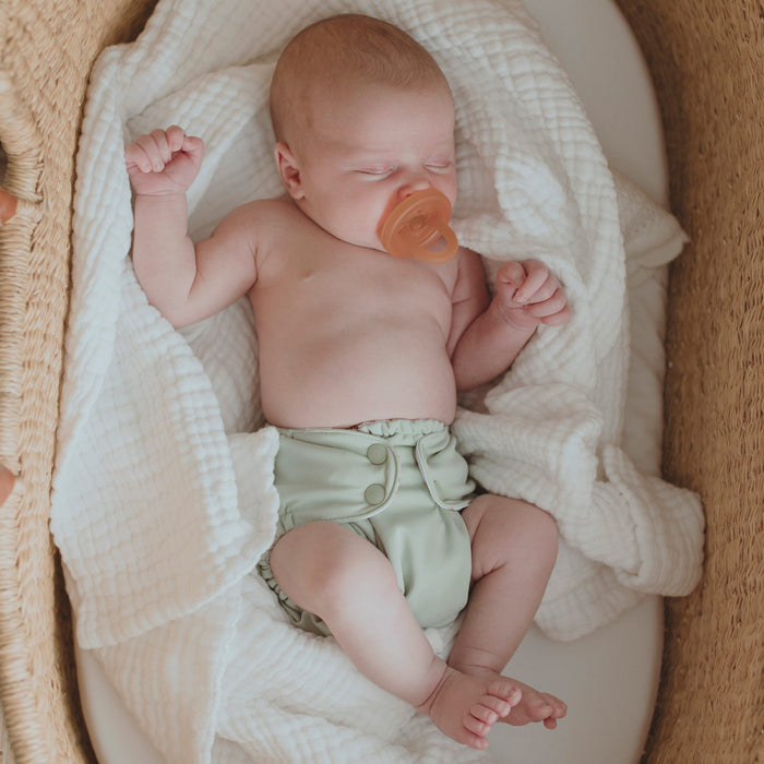A newborn baby wearing an Outer with a light mint green color