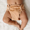 Baby wearing a light brown Outer laying on a white blanket