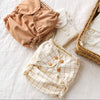 Sepia and Windowpane Outers on top of an Inner on a textured surface with a wicker basket filled with Inners