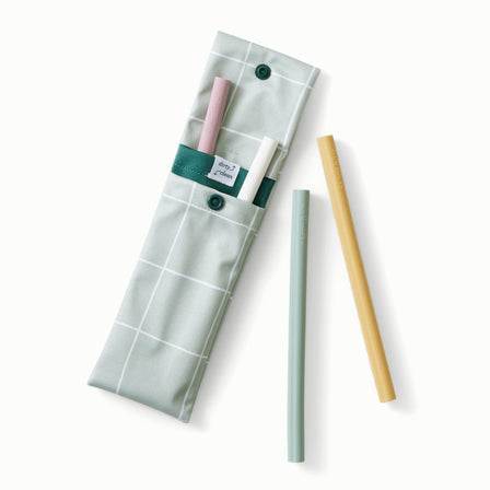 A Lattice print (a light green background with white lined grid pattern) straw pouch with dark green accents holding light purple, white, light green, and muted yellow silicone straws