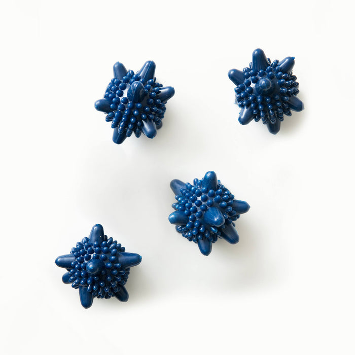 A set of four blue laundry ball agitators arranged on a white surface.