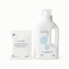 A white bottle of Esembly Softening Rinse next to a matching white packet of Softening Rinse Refill on a clean white background.