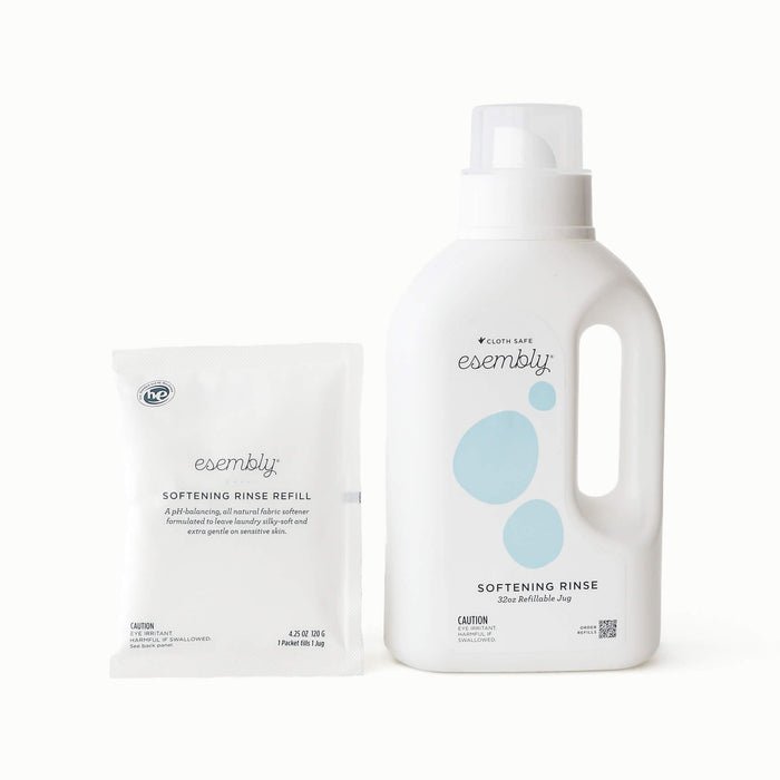 A white bottle of Esembly Softening Rinse next to a matching white packet of Softening Rinse Refill on a clean white background.
