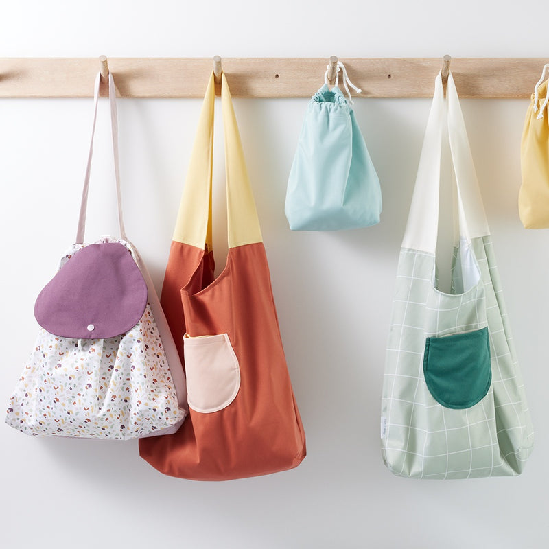Esembly bags; a Terrazzo Day Bag, a Clay Carryall, a Lattice Carryall, a Mist ditty bag, and a barley ditty bag.
