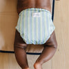 Striped cloth diaper worn by a child on a wooden floor