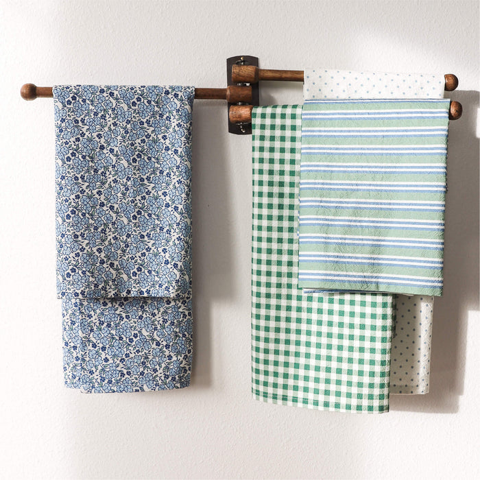 Set of patterned tea towels hanging on a wooden rack against a white wall.