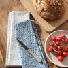 Tea Towels with floral pattern and polka dots on a wooden surface with bread and tomatoes