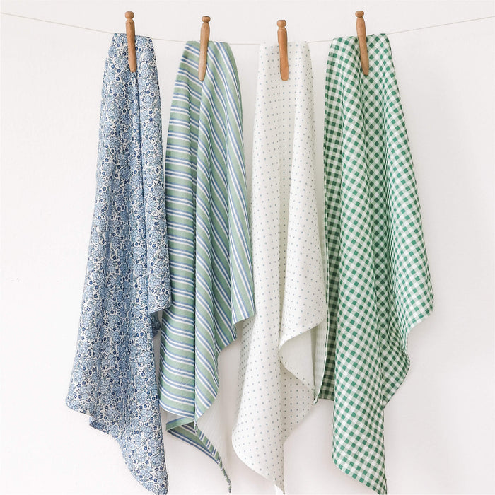 Four patterned tea towels hanging on a line against a white background