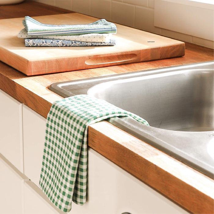 Kitchen sink area with wooden countertop, cutting boards, and green checkered towel.